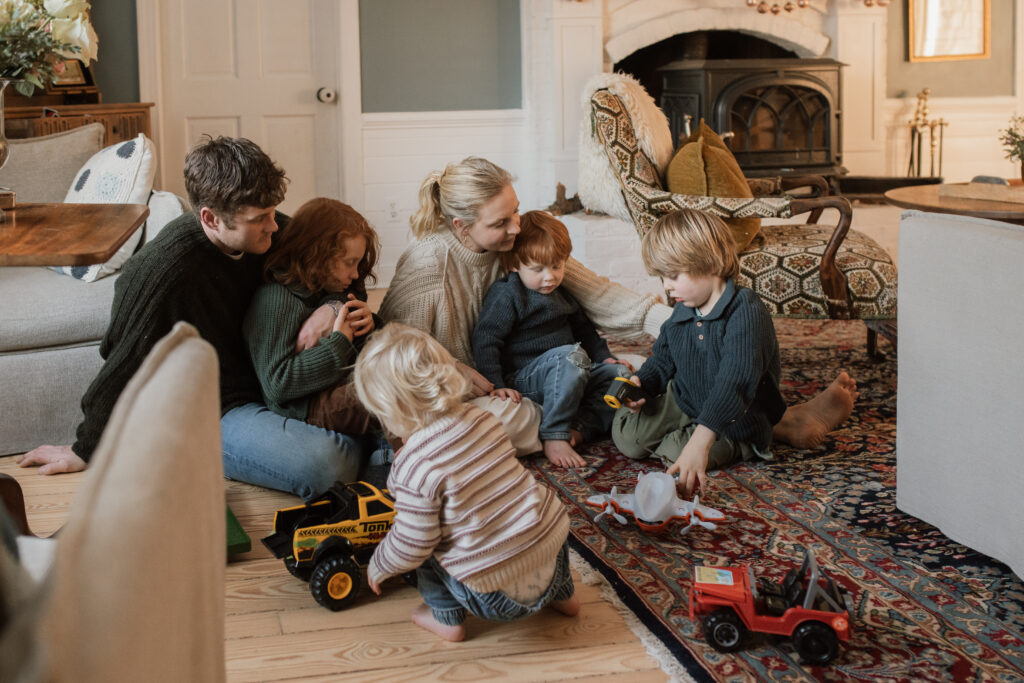 Family with four boys plays on the floor during family photos at home