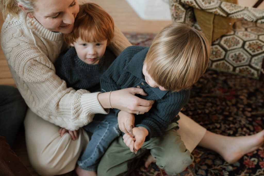 Family with four boys plays on the floor during family photos at home