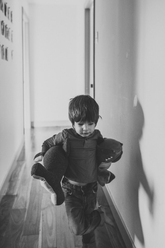 Toddler boy plays with stuffed animals as an example of winter family photo outfits