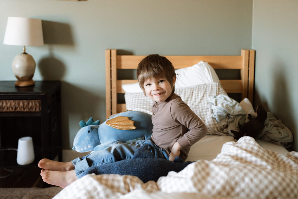 Toddler boy sits on the bed an example of winter family photo outfits