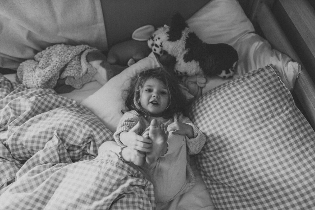 Toddler girl plays in her bed as an example of winter family photo outfits