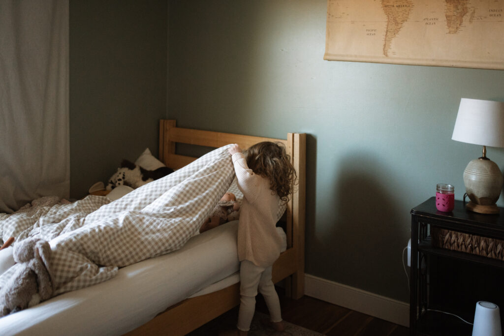 Toddler girl plays with dolls in her room as an example of winter family photo outfits