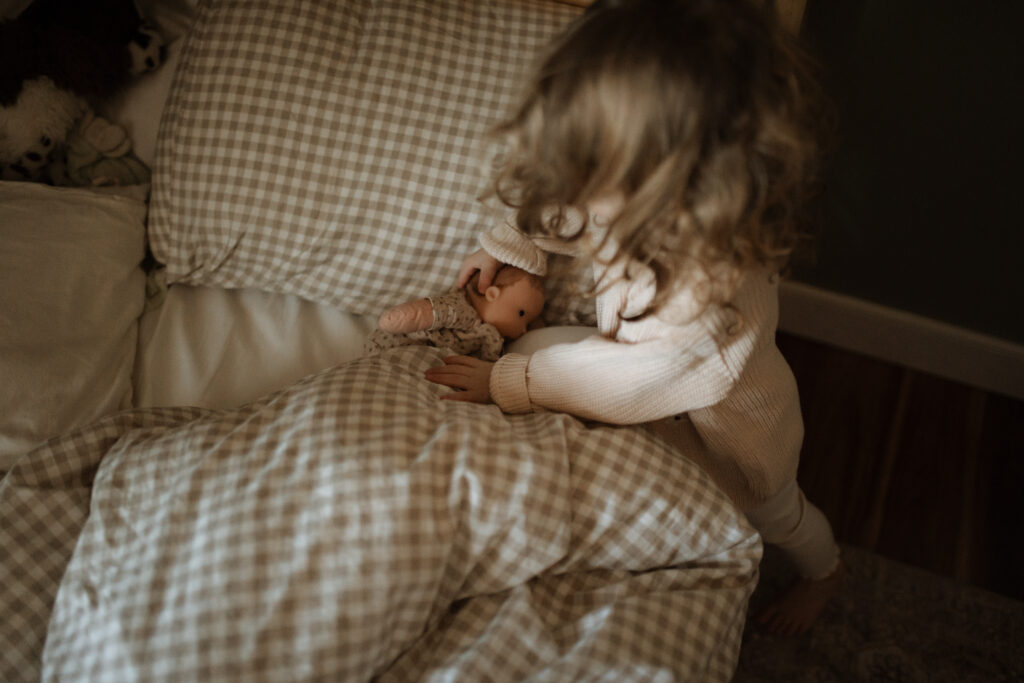 Toddler girl plays with dolls in her room as an example of winter family photo outfits