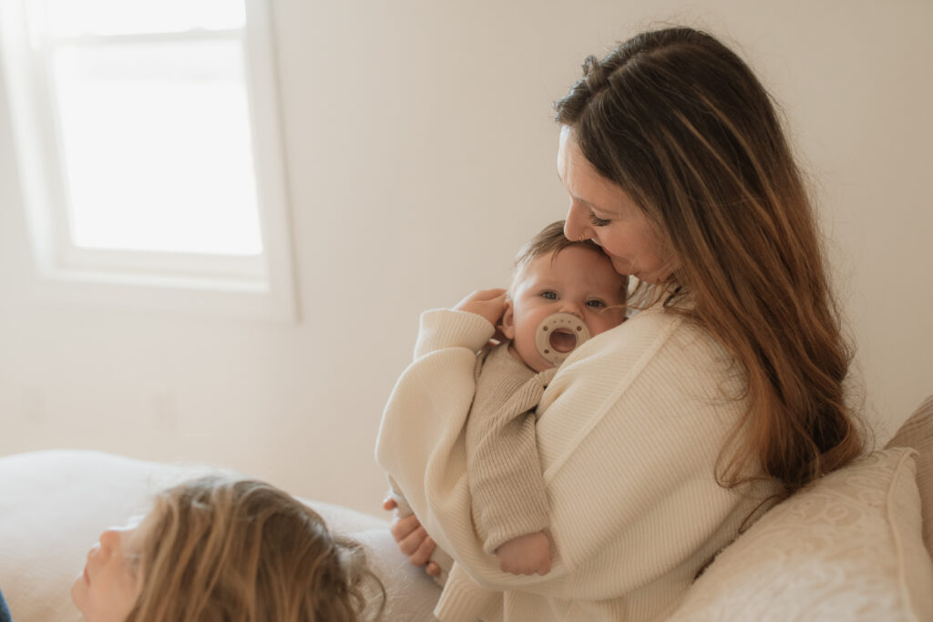 Mom and baby snuggle on the bed as an example of winter family photo outfits