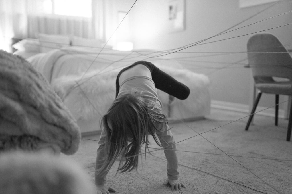 Girl completes yarn maze as an example of family activity to do at home. 