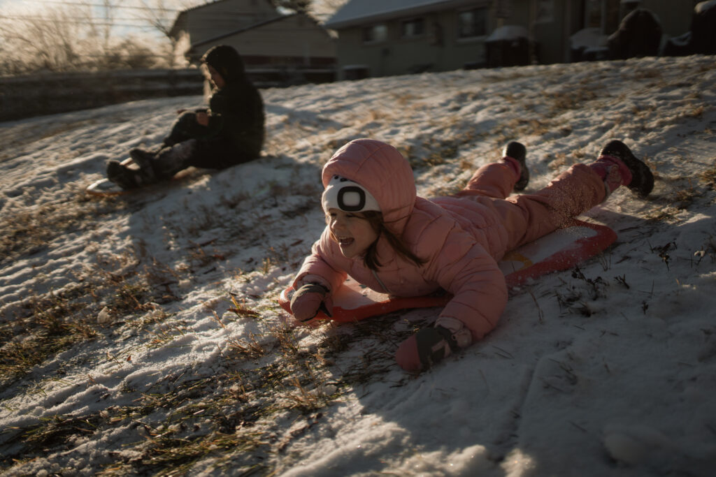 Boy and girl sledding as an example of snow photo ideas 