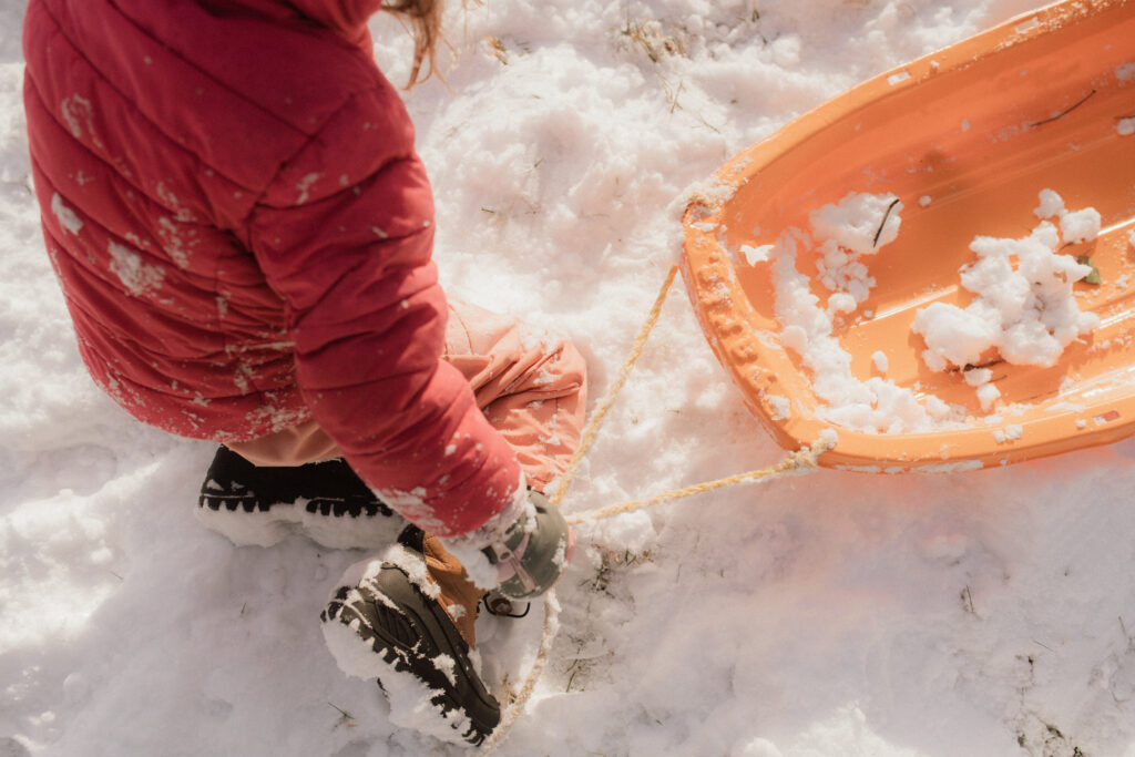 Girl with sled in the snow as an example of snow photo ideas