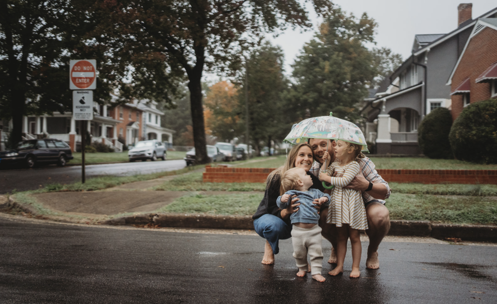 Family huddles under umbrella in the rain for spring family photos in Richmond, VA 